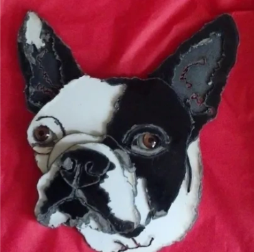 A fabric patch depicting a black and white dog face on a red background.