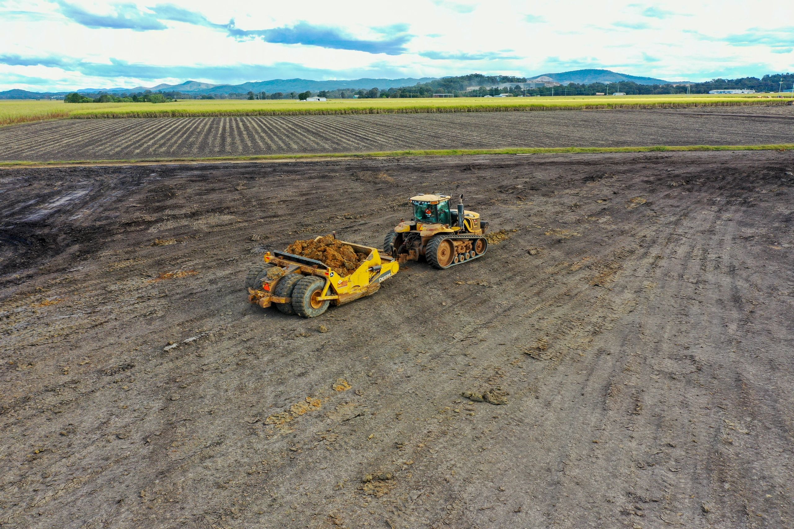 Tractor scraper levelling a paddock — aerial view