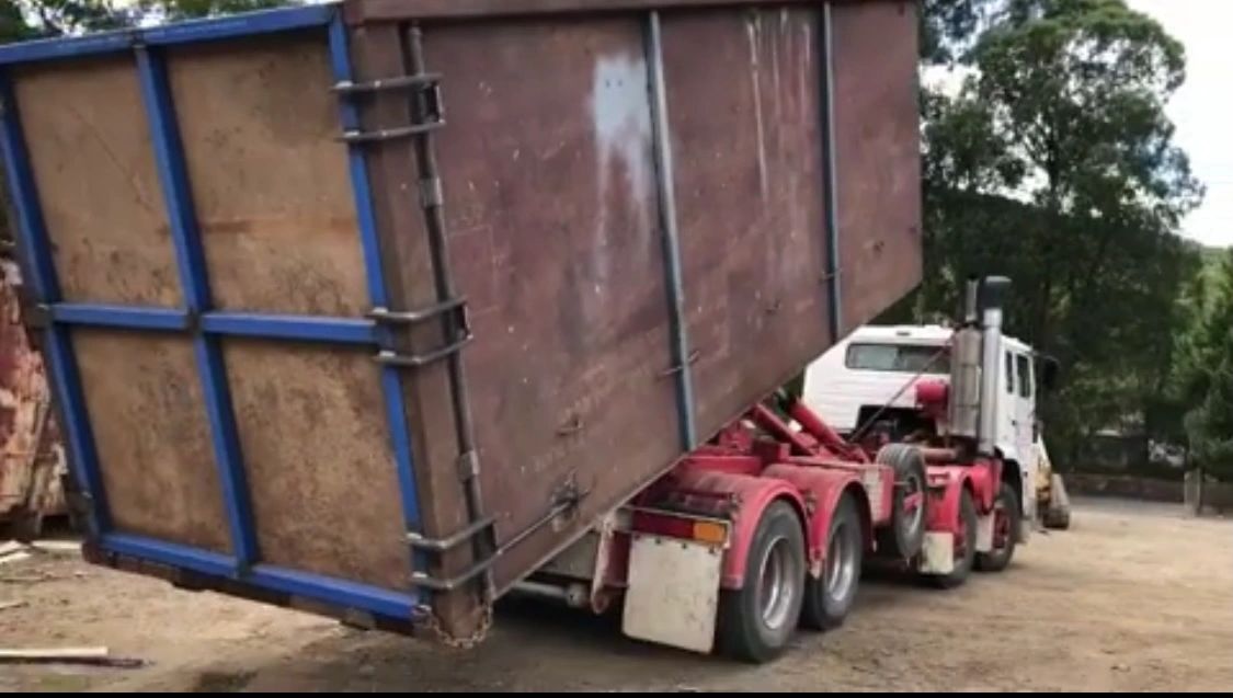 Skip bin being loaded onto hook-lift truck