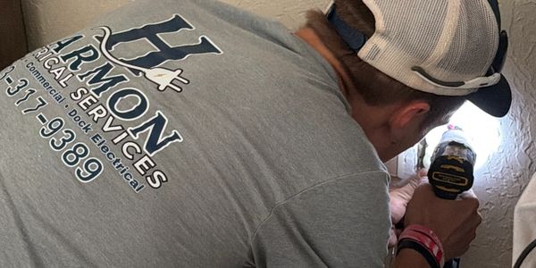 Electrician working on wall outlet wiring inside a house.