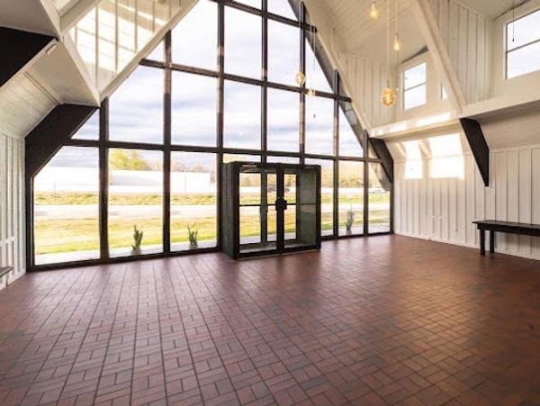 A-frame building with white walls and ceiling and black trim accents. Red tile floor.