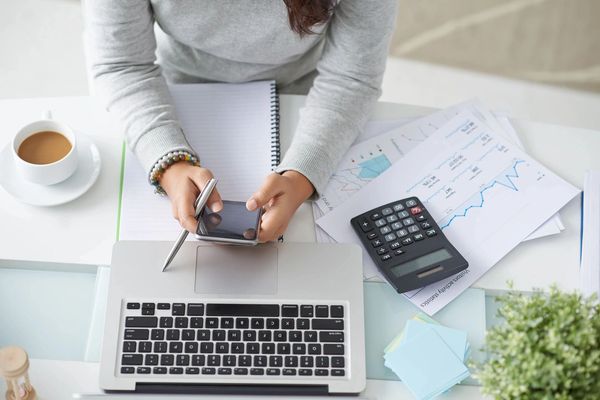 Financial manager using smartphone at her workplace, view from the top
