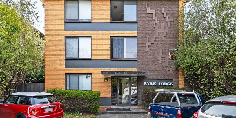 Front view of a brick apartment building with parked cars outside.
