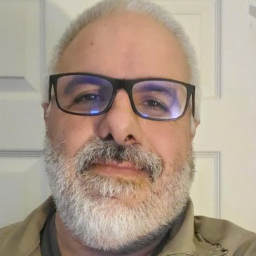 Smiling man with glasses and gray beard.