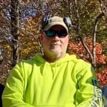 Man wearing a neon yellow hoodie and sunglasses outdoors.