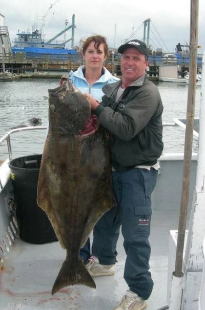 Captain Randy holds up a 50-lb halibut for this happy angler.