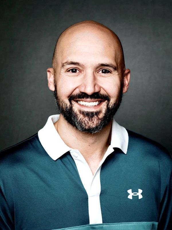 Smiling bald man with a beard in a sports shirt.