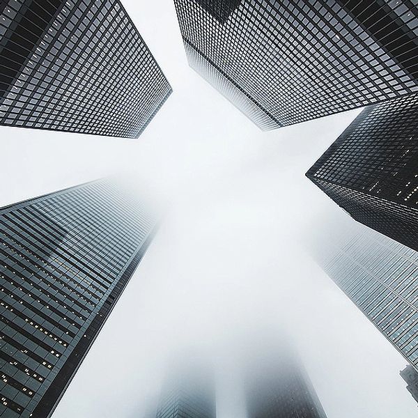 Foggy skyscrapers viewed from below in a city.