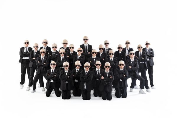 Group of children in suits and sunglasses with bald caps.
