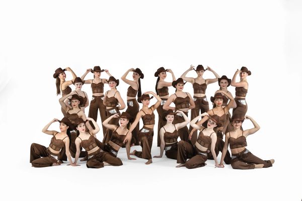 Group of women in brown outfits posing with hats.