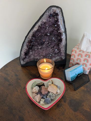 Amethyst geode with candle and stones on a wooden table.