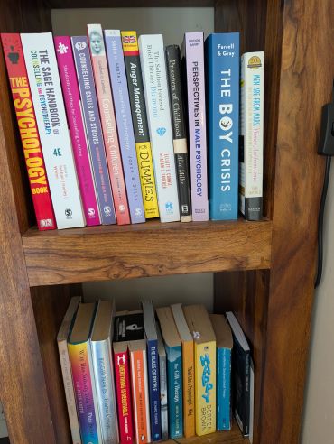 Books on psychology and related topics arranged on wooden shelves.