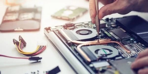 Hands repairing a laptop's internal components with a screwdriver.