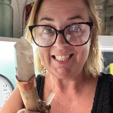 Woman smiling and holding a large crystal wand.