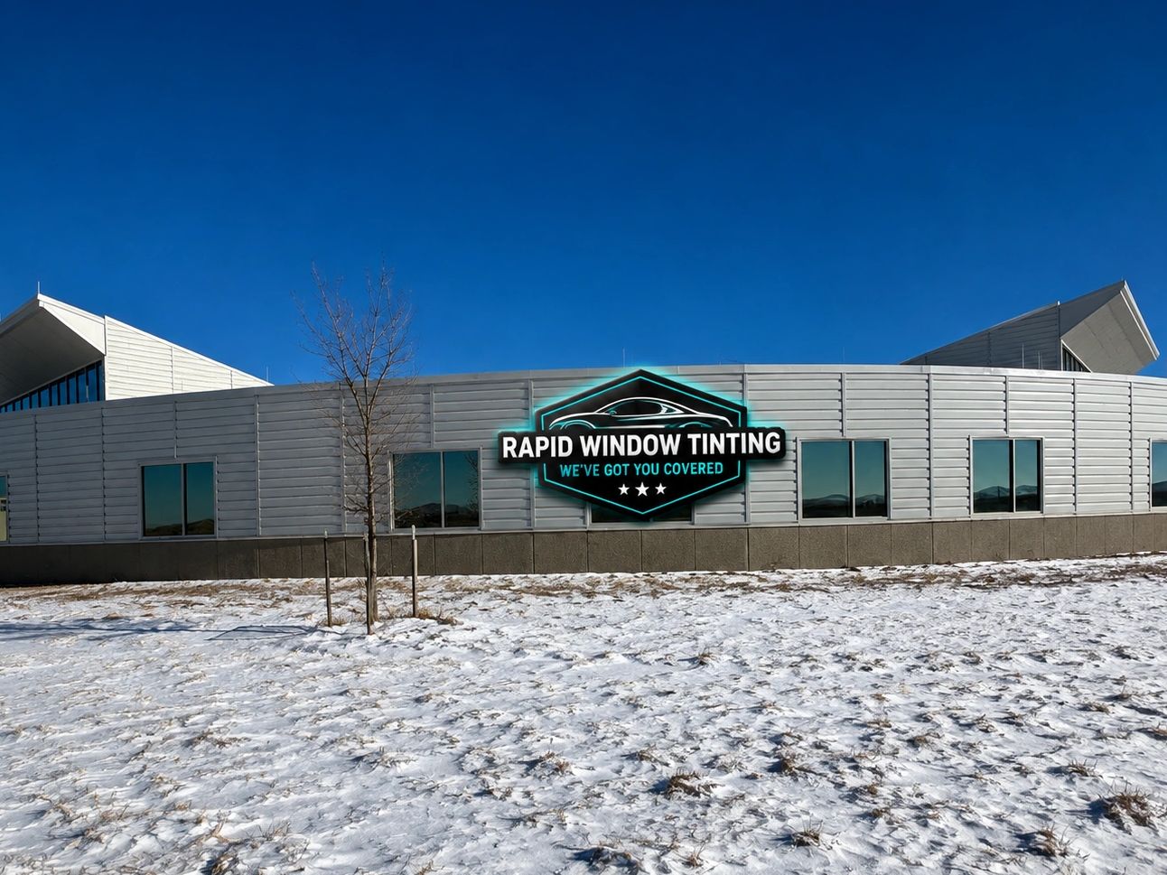 Modern building with a sign for Rapid Window Tinting in snowy landscape.