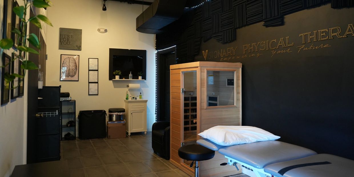 Modern physical therapy room with treatment bed and wooden sauna.