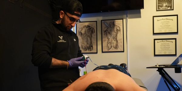 Therapist performs treatment on a shirtless patient in a clinic.