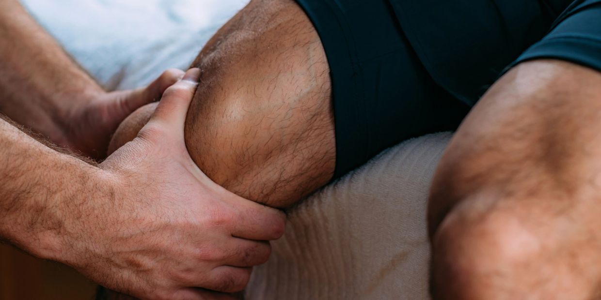 A person massaging a sore knee with both hands.