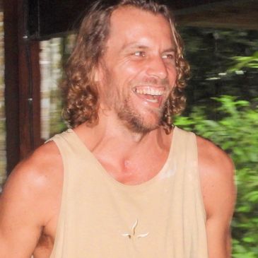 Hombre sonriente con camiseta sin mangas beige.