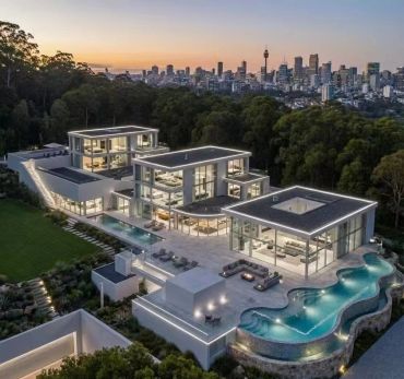 Luxurious modern mansion with illuminated pool and city skyline at sunset.