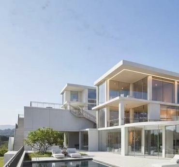 Modern luxury house with large glass windows and a swimming pool.