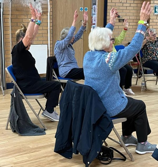 Older adults exercising with arms raised while seated.