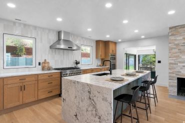 Modern kitchen with marble island and wooden cabinets.