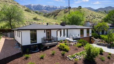 White house with black trim and mountain backdrop.
