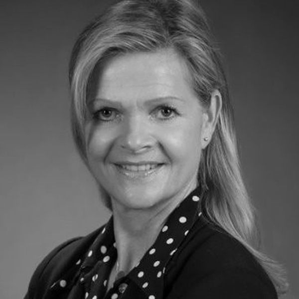 Black and white portrait of a smiling woman with light hair and polka dot blouse.