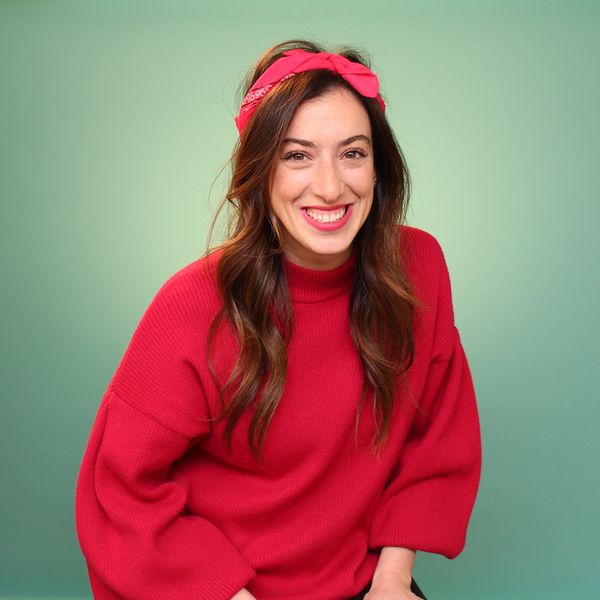 Smiling woman in a red sweater and matching headband against a green backdrop.