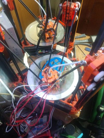 3D printer with orange components and multiple wires.