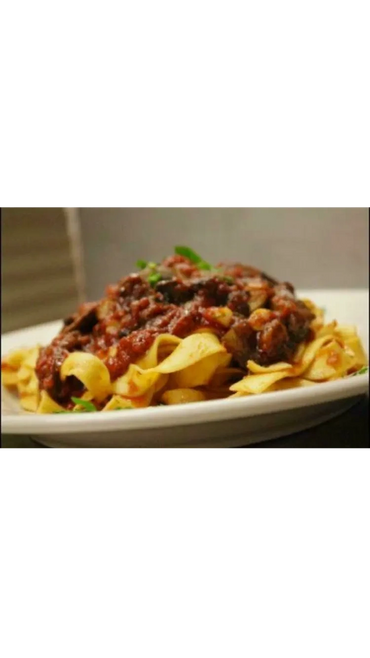 Plate of pasta with rich tomato meat sauce.