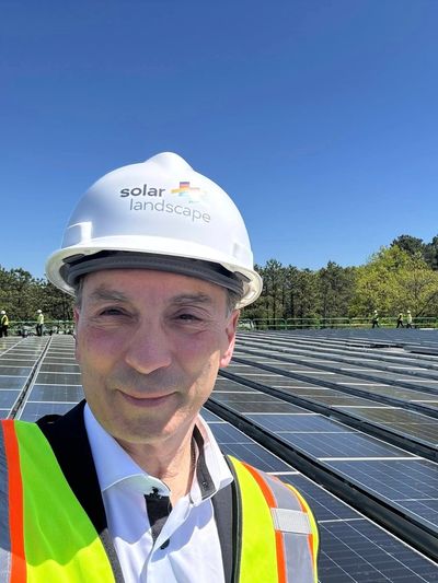 Man in safety vest and helmet at solar panel installation site.