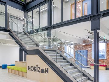 Modern office staircase with glass railings and Horizon logo.