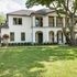Elegant two-story white house with a large tree and manicured lawn.