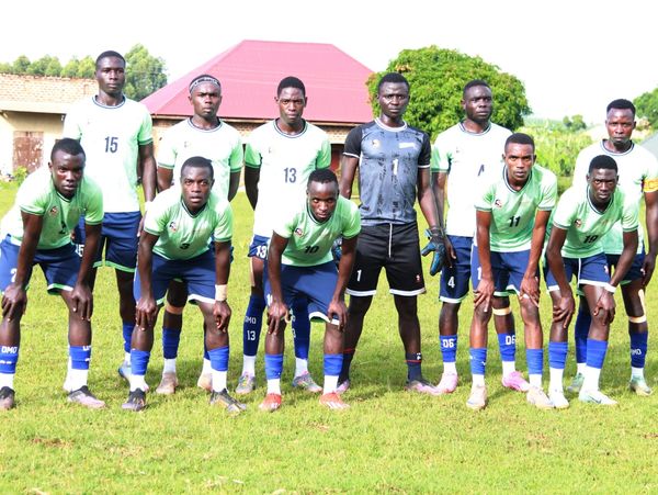 A soccer team posing on a grassy field in their uniforms.