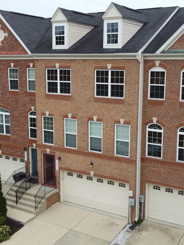 Row of brick townhouses with garages and multiple windows.