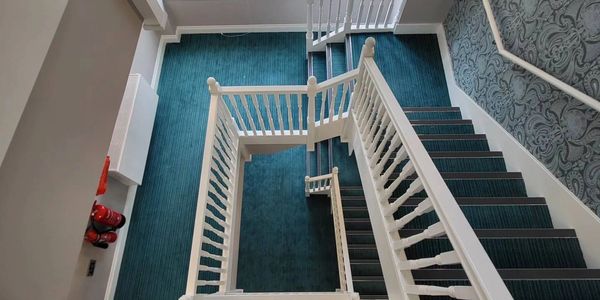 stairwell with turquoise carpet and white banisters. communal cleaning. commercial cleaning. 