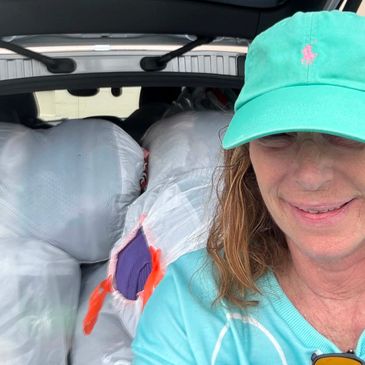 Woman in green cap with packed car trunk.