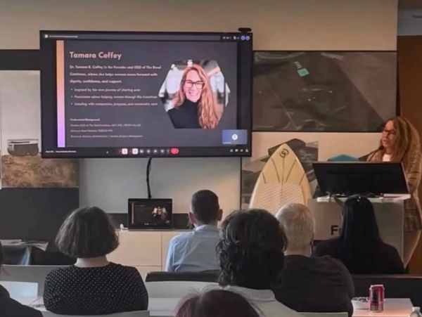 A woman presenting Tamara Coffey's profile to an audience.