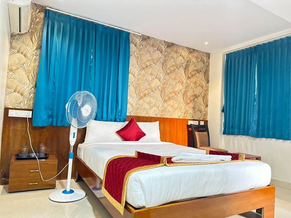 Cozy hotel room with blue curtains and a stand fan.