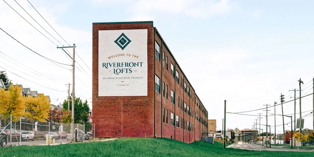 Captivating riverfront loft building featuring modern architecture, large windows, & brick exterior