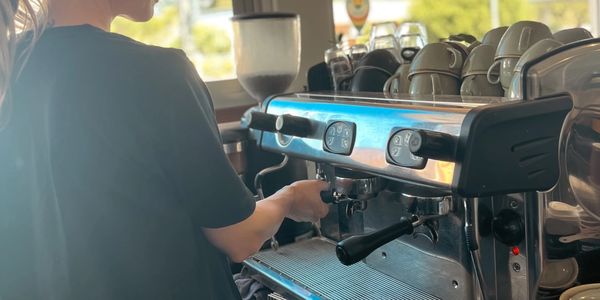 A barista preparing coffee with an espresso machine in a cafe.