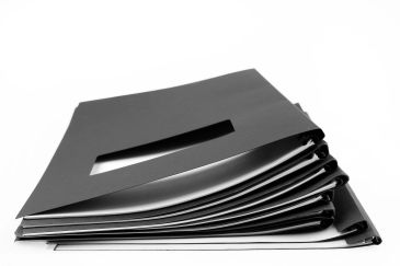 A stack of black folders with a cut-out window on top.