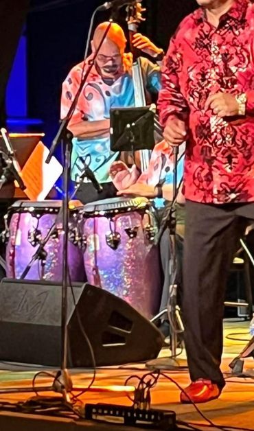 Musicians performing live with colorful shirts and instruments on stage.