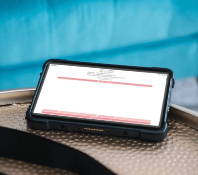 Tablet resting on a metallic surface with blurred background.