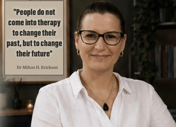 Smiling woman with glasses beside a therapy quote by Dr. Milton H. Erickson.