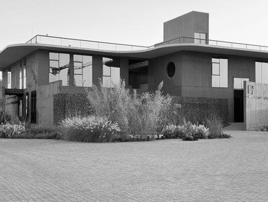 Modern two-story building with plants in front.