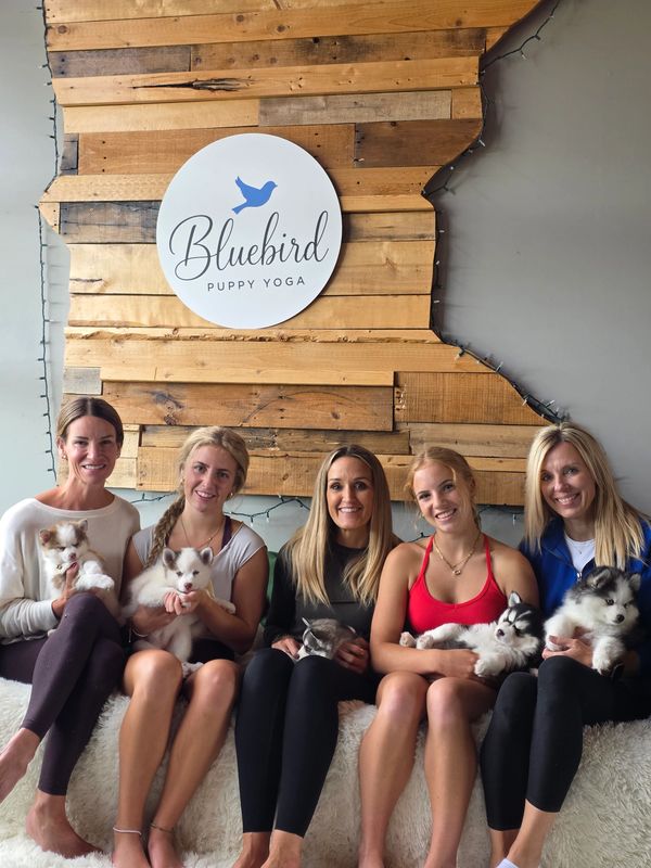 Five women holding puppies at Bluebird Puppy Yoga.
