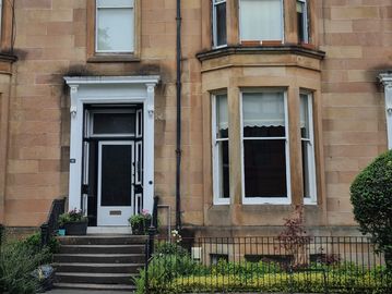 Entrance of a stone townhouse with bay window.